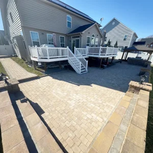 Stone patio with gazebo and white deck in back of house