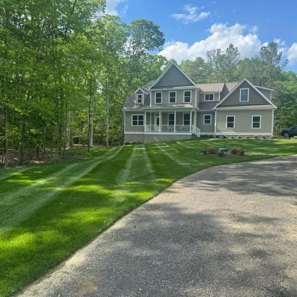 gravel driveway leading to house with large freshly mowed lawn